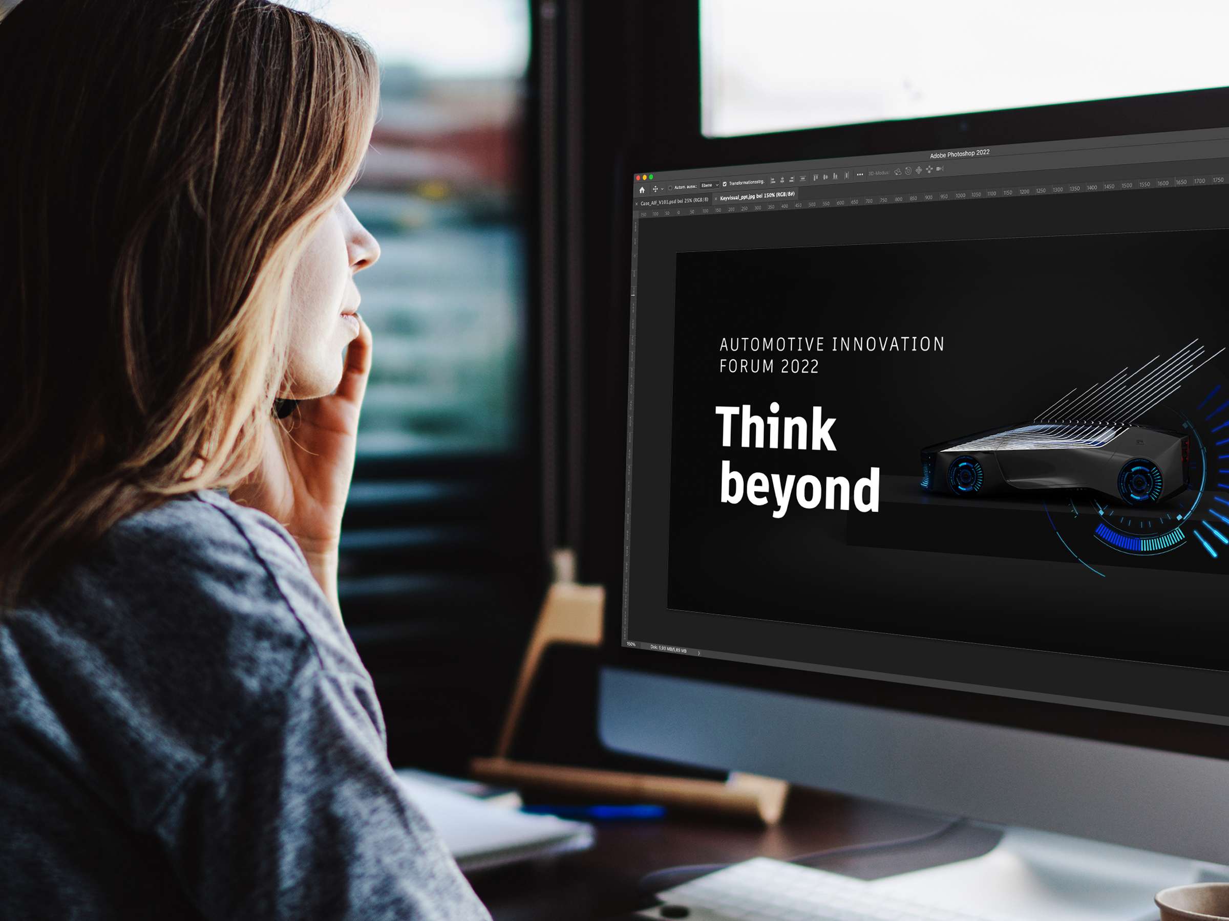 Woman sitting at a monitor on which the page for the Automotive Innovation Forum 2022 is displayed.