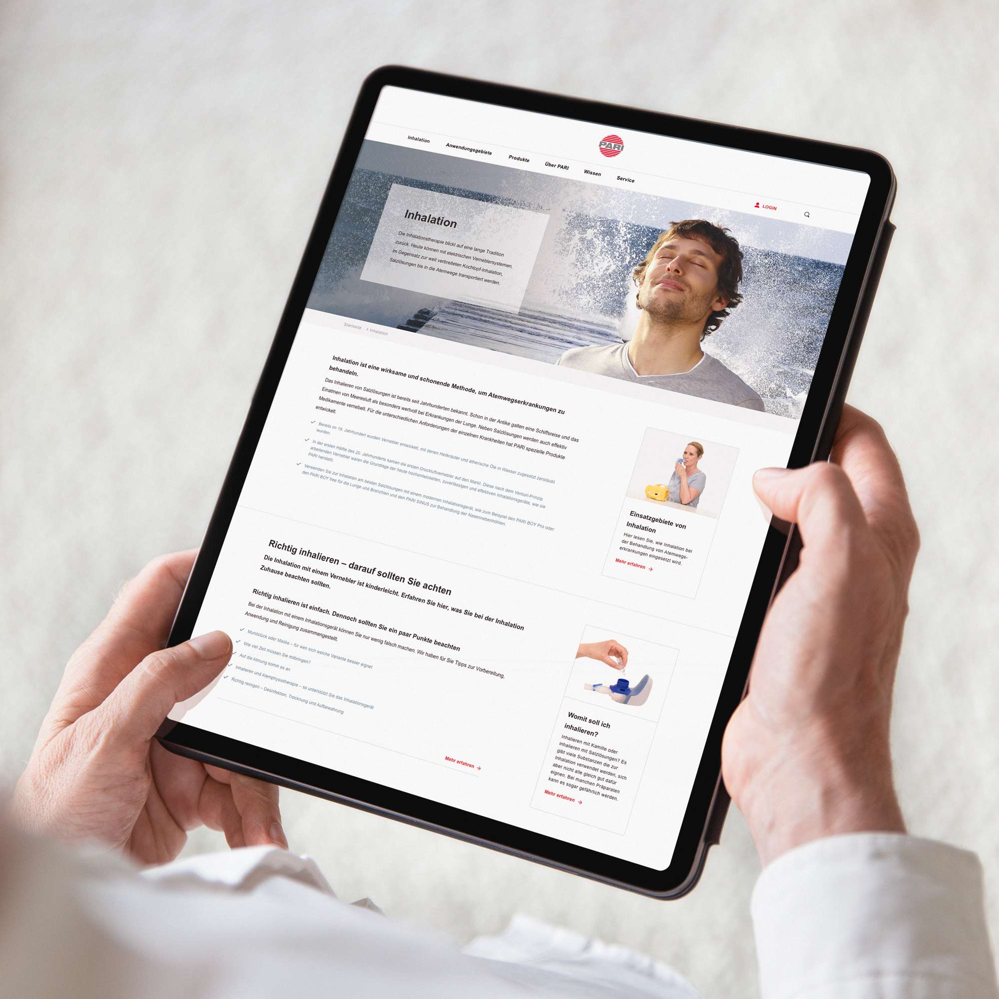 Two hands holding a tablet on which a view of the PARI website can be seen with multiple content modules