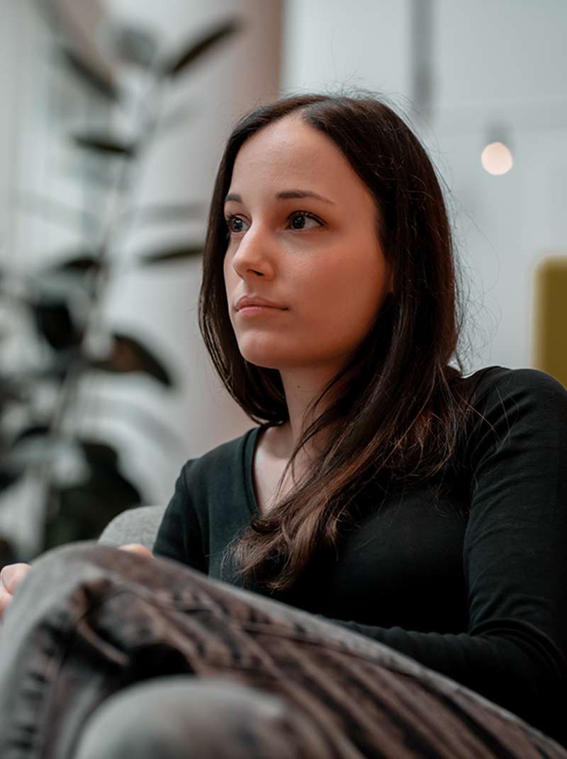 Sarah looks thoughtfully into the distance. The coworking space can be seen in the background.