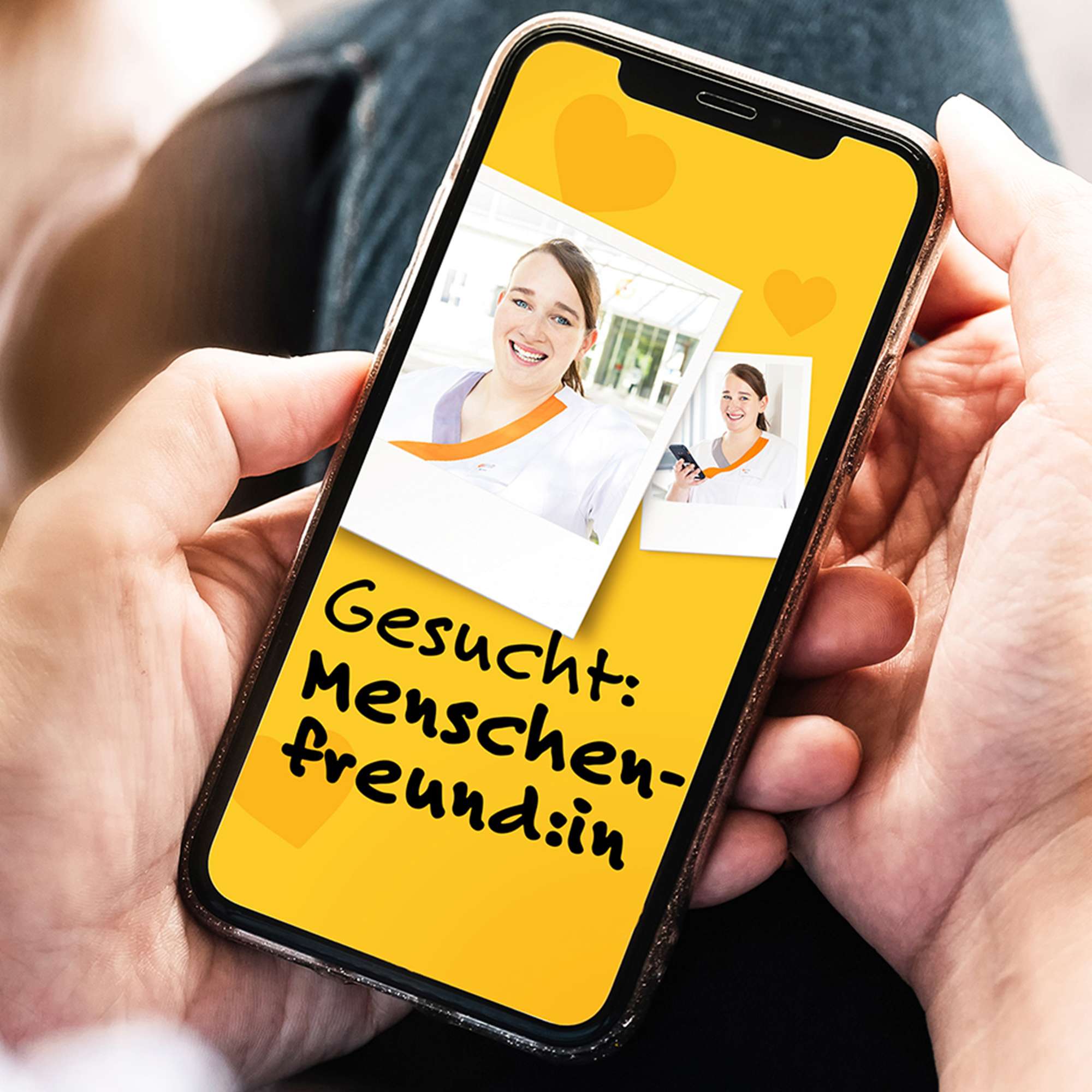 Zwei Hände halten ein Smartphone, in dem eines der Keyvisuals aus der Personalkampagne der Schön Klinik in einem Polaroid-Foto zu sehen ist, daneben der Claim „Gesucht: Menschenfreund:in“
