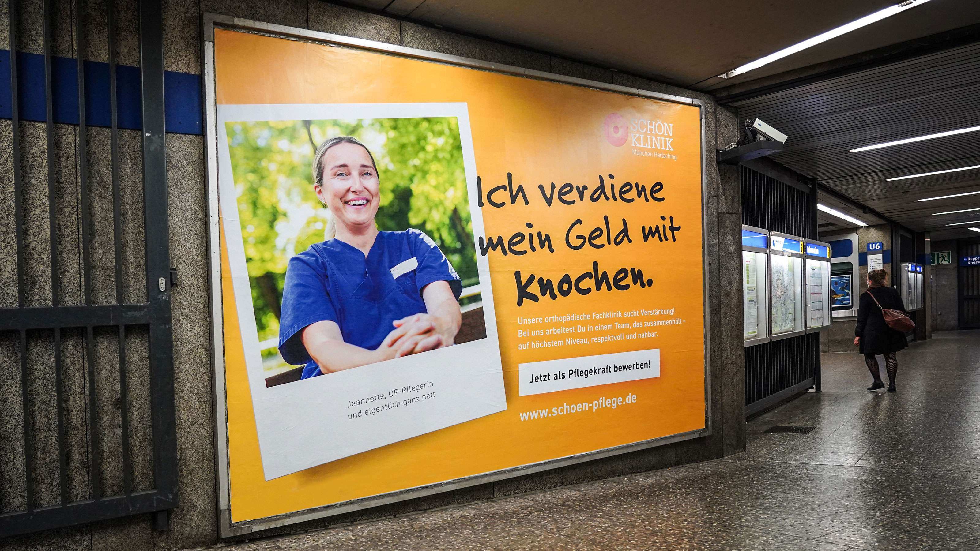 Großes U-Bahn-Plakat aus der Personalkampagne der Schön Klinik an einer Rolltreppe an einem U-Bahn-Bahnhof am Eingang eines U-Bahnhofes: Polaroid-Bild einer Pflegekraft neben dem Claim „Ich verdiene mein Geld mit Knochen“ und dem Aufruf, sich jetzt als Pflegekraft zu bewerben und dem Logo der Schön Klinik