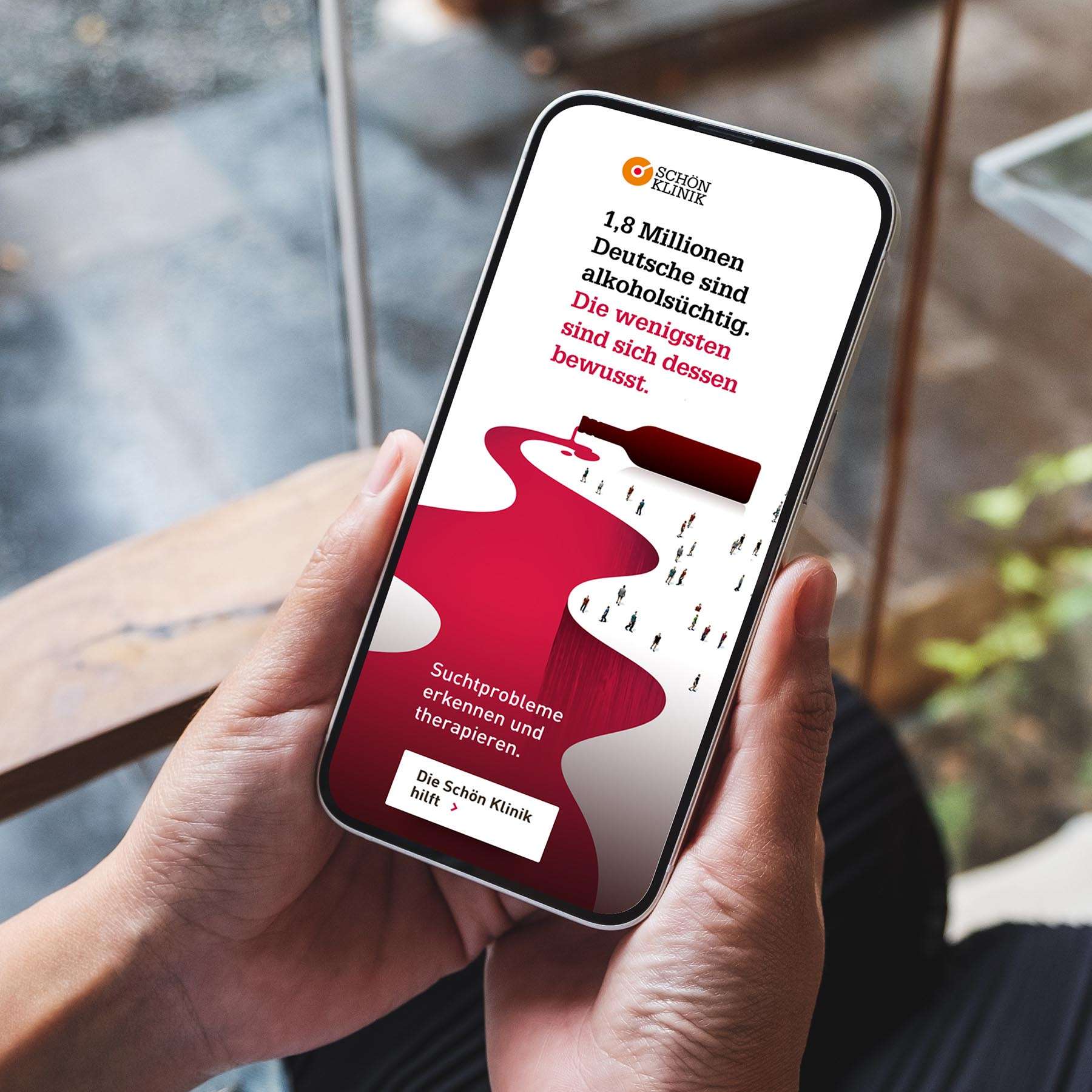 Two hands hold a smartphone on which an ad from the Schön Klinik's social media campaign on alcohol addiction can be seen.